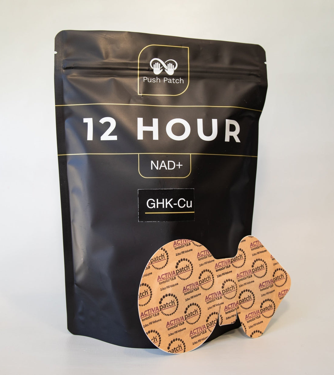 A black resealable package labeled “12 HOUR NAD+ GHK-Cu” from Push Patch, displayed with two tan ACTIVApatch adhesive patches designed for transdermal delivery, placed in front of the packaging.
