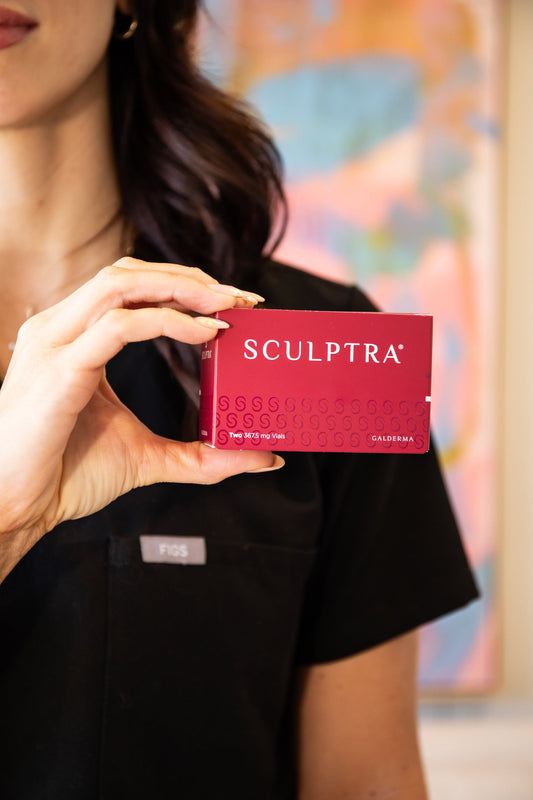 A woman in a black uniform holding a red Sculptra® box in front of her chest, with the brand name clearly visible and a colorful abstract background behind her.