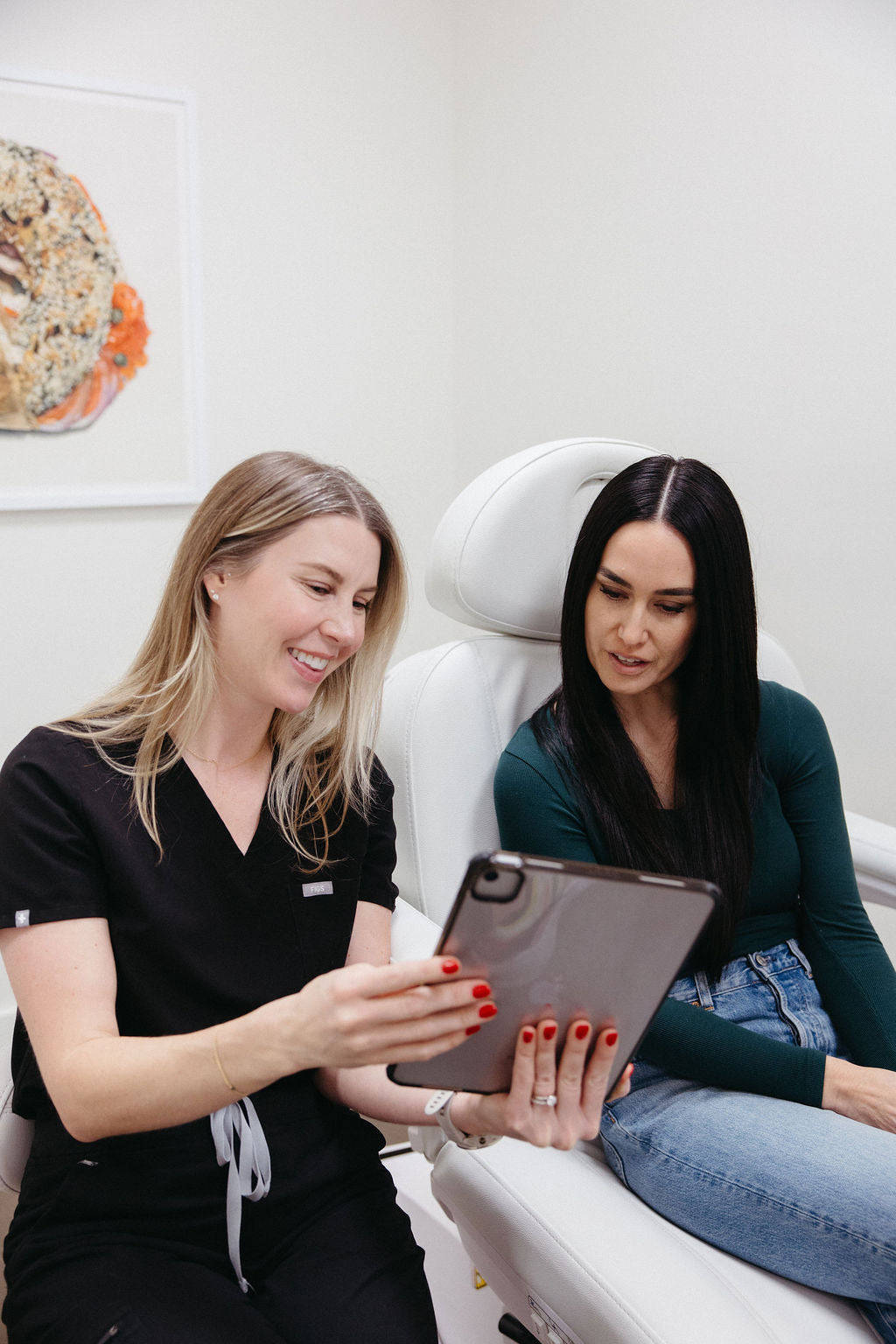 Blonde, female nurse practitioner reviewing lab results with a brunette, female patient.