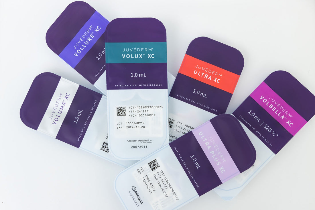 Flat lay of six JUVÉDERM® filler packages — Vollure XC, Volux XC, Ultra XC, Voluma XC, Volbella XC, and Ultra Plus XC — fanned out on a white background.