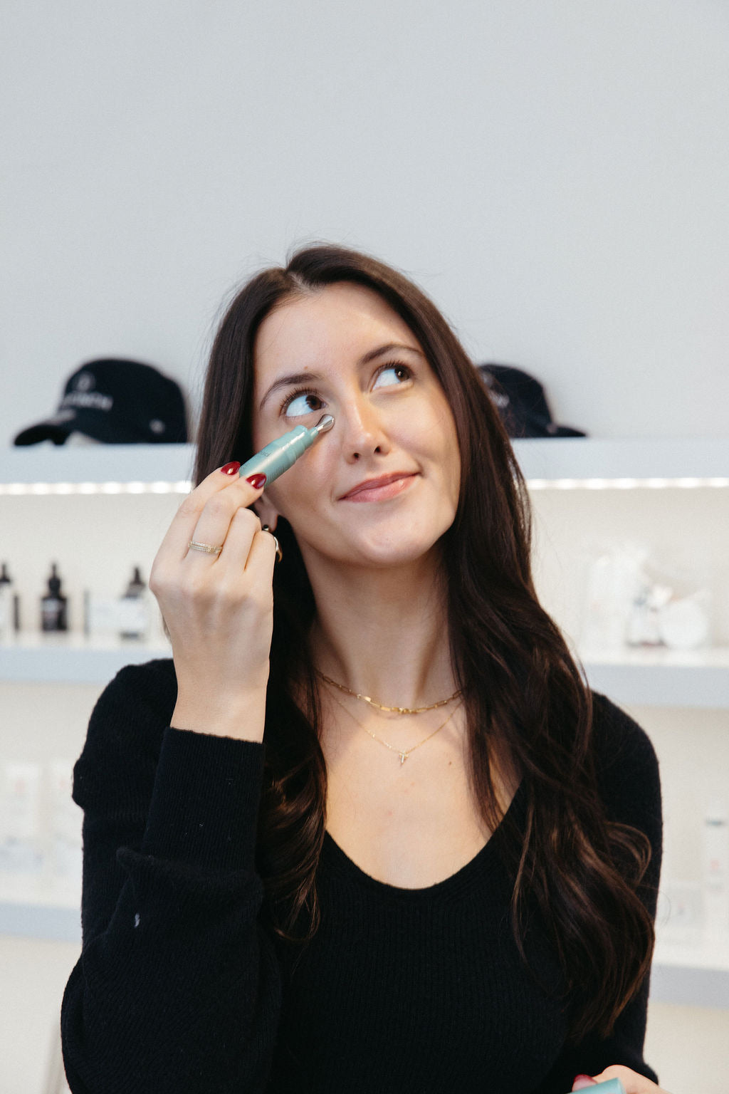 Woman applying an under-eye skincare tool in a bright cosmetic dermatology clinic.