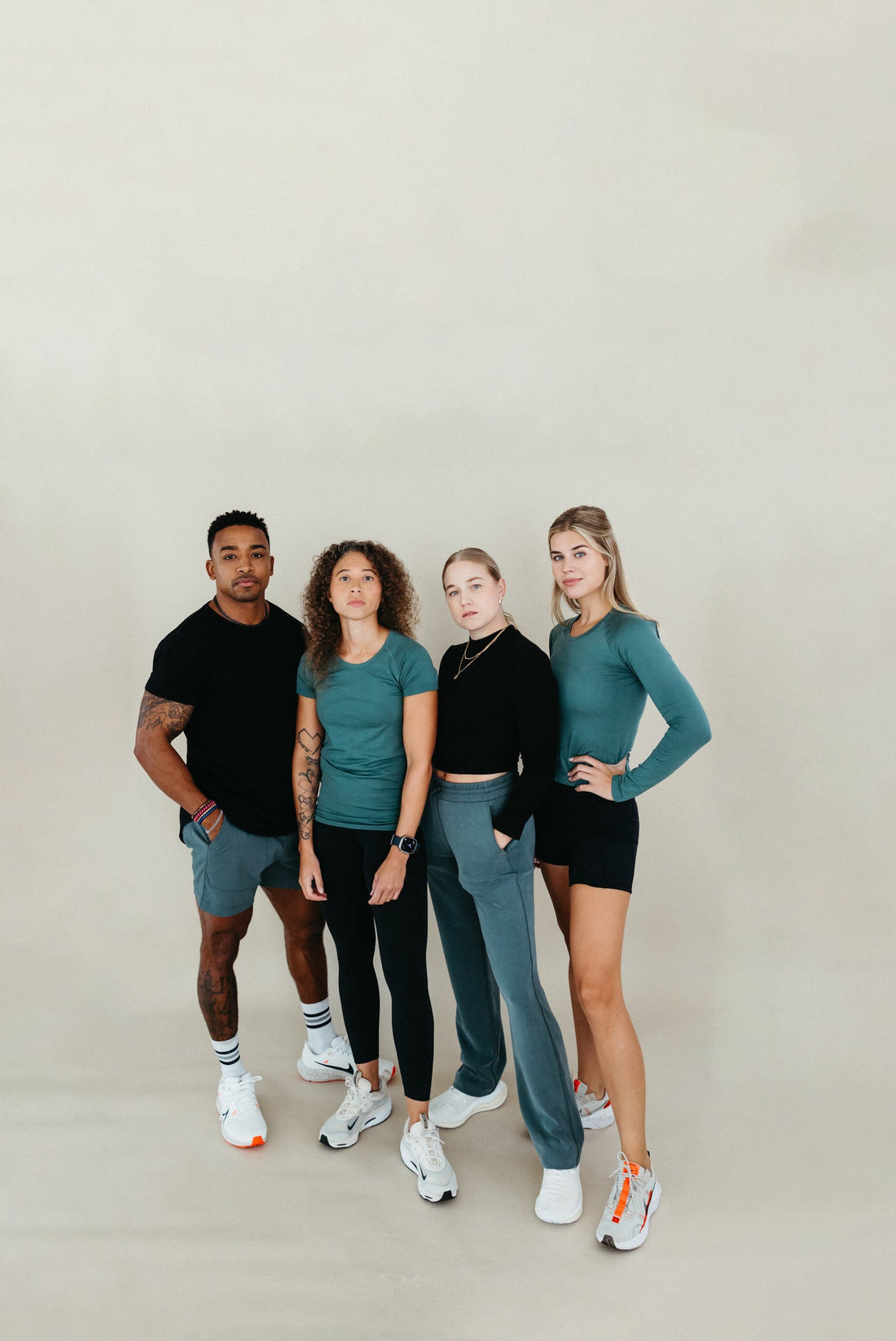 4 Athletes in black and sage green workout outfits