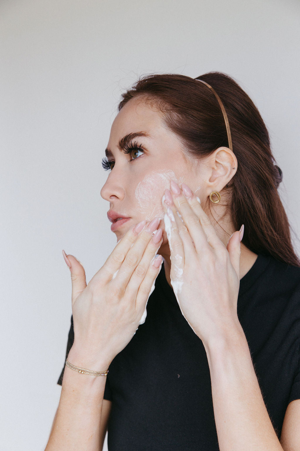 Woman gently cleansing her face with a foaming facial cleanser, demonstrating a skincare step to prep skin before makeup application.