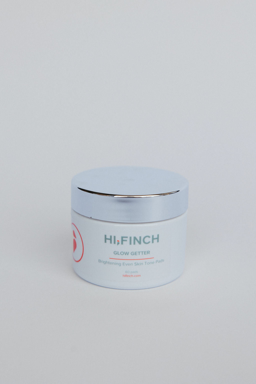 "White jar of Hi, Finch Glow Getter brightening pads with a silver lid, labeled Brightening Even Skin Tone Pads, 60 pads, against a plain light gray background."