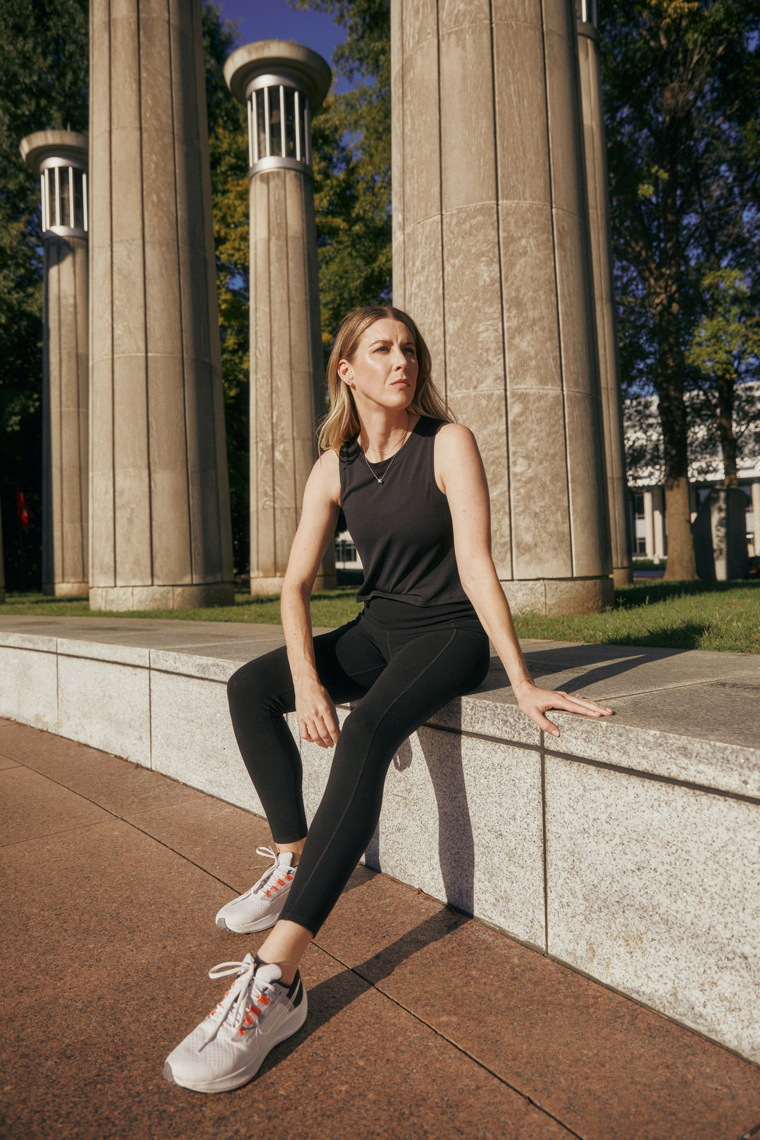 Blonde woman sitting on a concrete bench.